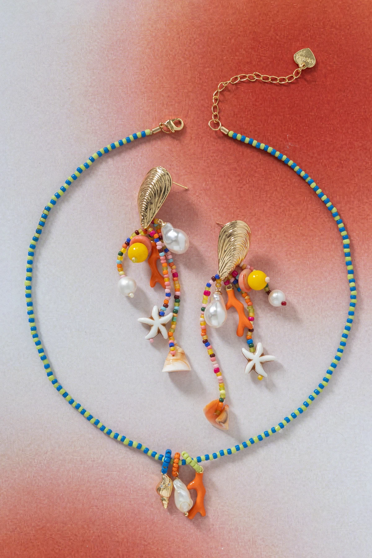 Colorful necklace and earrings arranged on a coral background