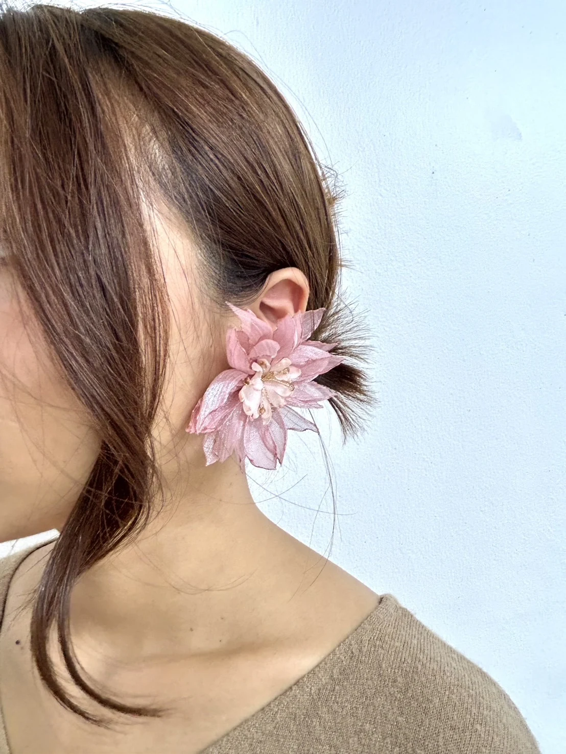 Pink floral statement earring worn beside a short hairstyle