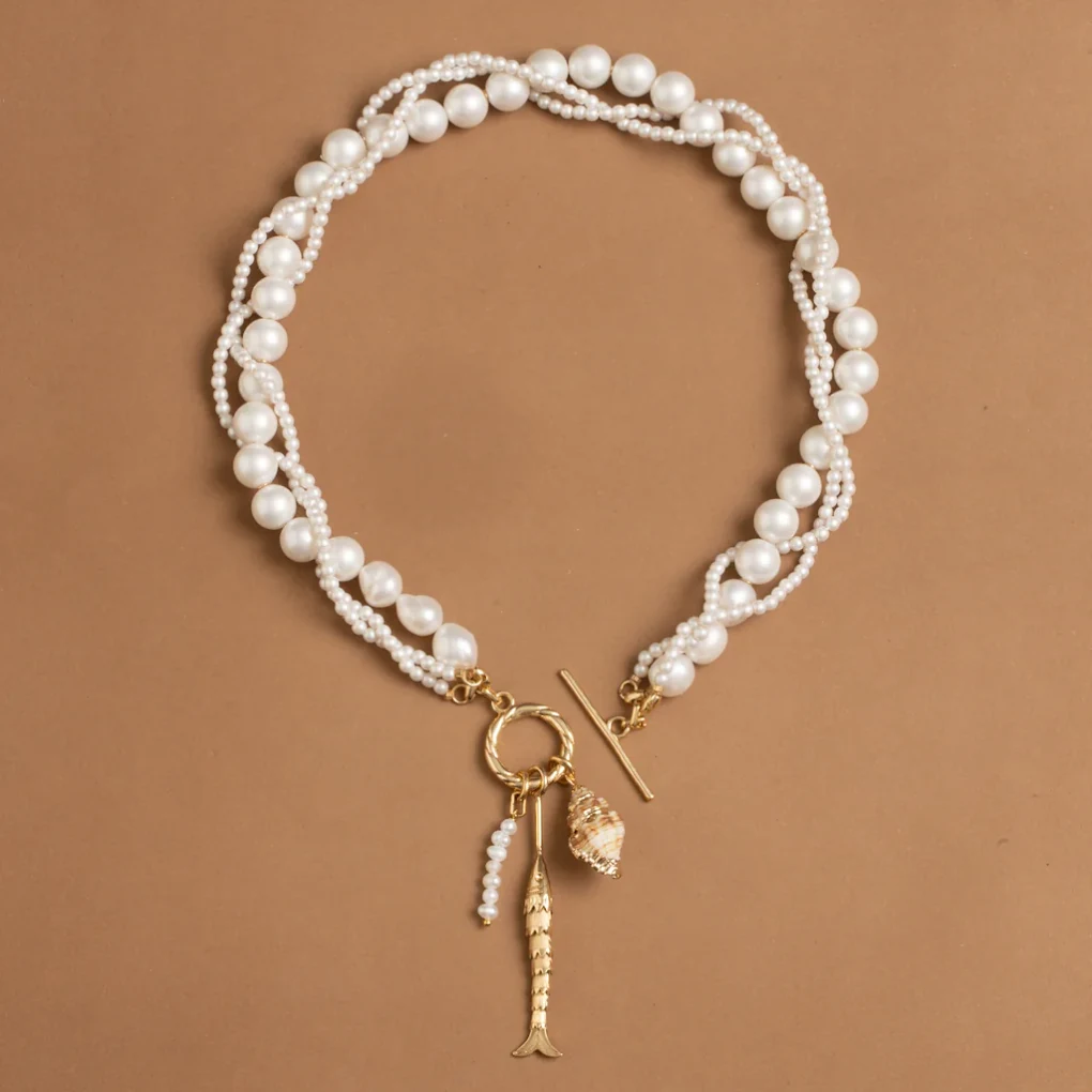 White beaded necklace with gold-tone charms on a brown background